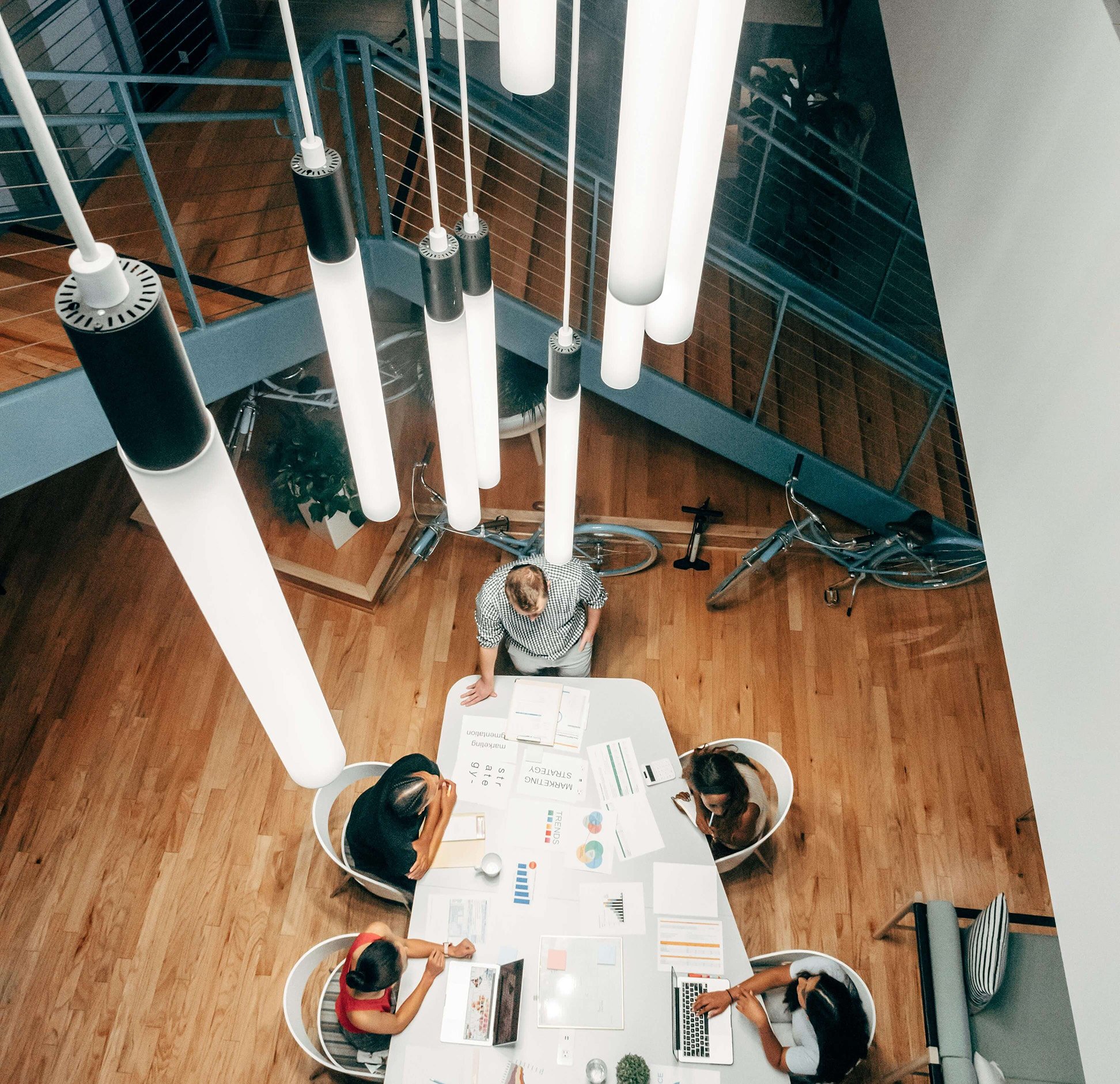 Overhead view of a conference table with 5 people working looking at papers and laptops